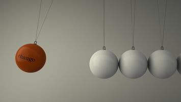 An orange ball with the word "change" written on it, about to hit a row of static white balled suspended by wire